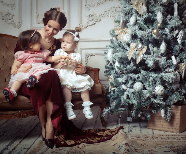 Young mother and her two little daughters near Christmas tree 