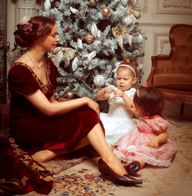 Young mother and her two little daughters near Christmas tree