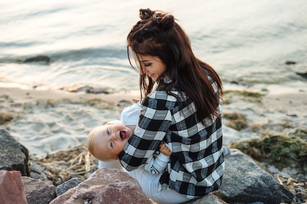 写真 ビーチで屋外で幼児を抱っこしている若い母親