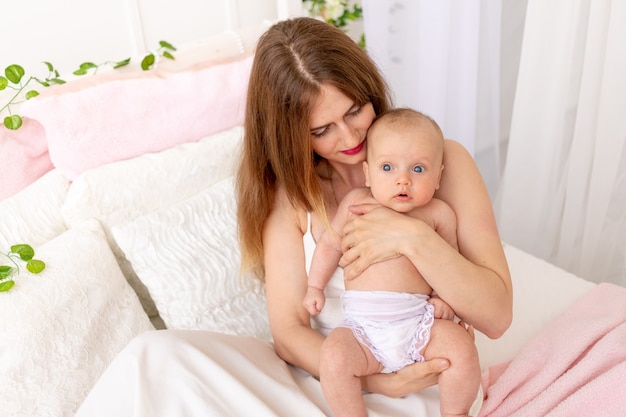 a young mother holds a child in her arms and admires it in a beautiful interior