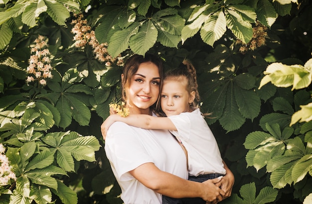 Young mother holds her daughter in the summer. Beautiful family and joy of motherhood.