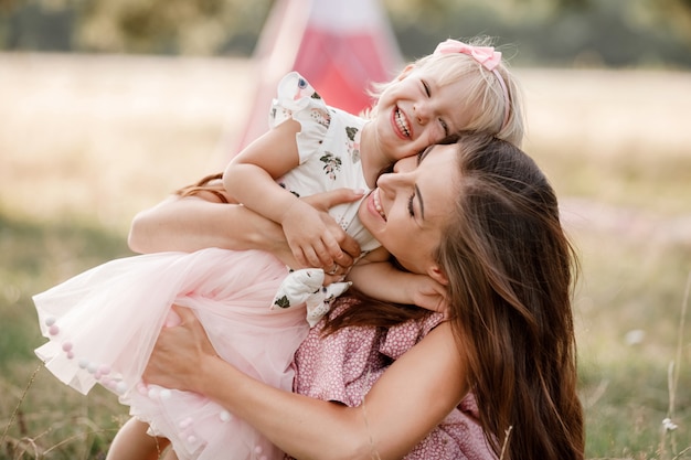 Young mother hugging baby girl and playing in summer park