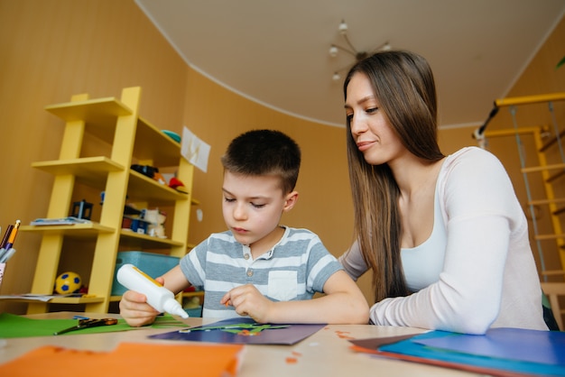 Giovane madre sta facendo i compiti con suo figlio a casa. genitori e formazione