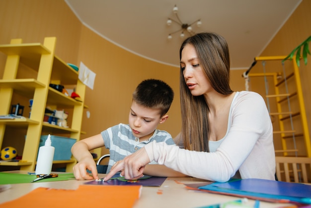 A young mother is doing homework with her son at home