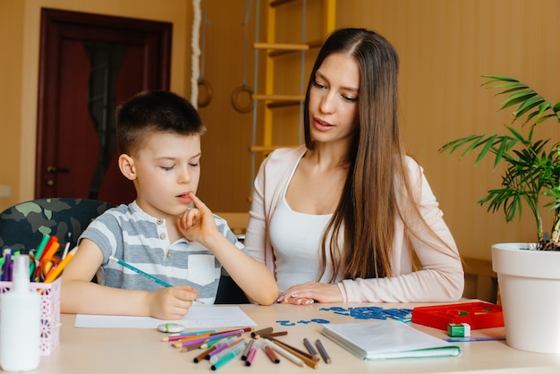 A young mother is doing homework with her son at home