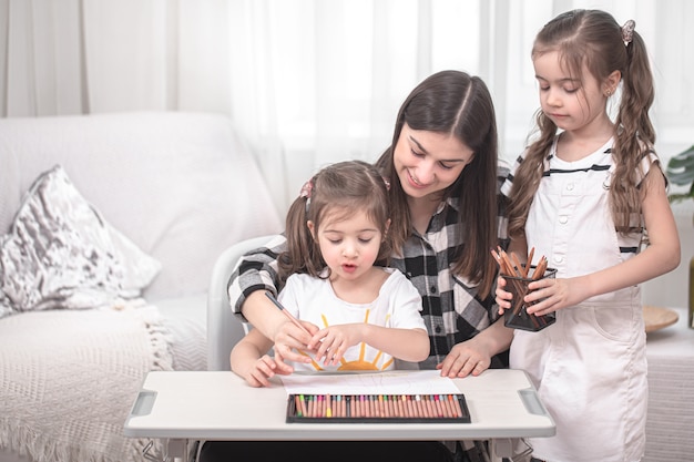 Young mother is doing homework with little daughters. Home schooling and education  