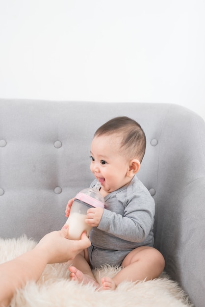 Young mother is feeding her baby at room