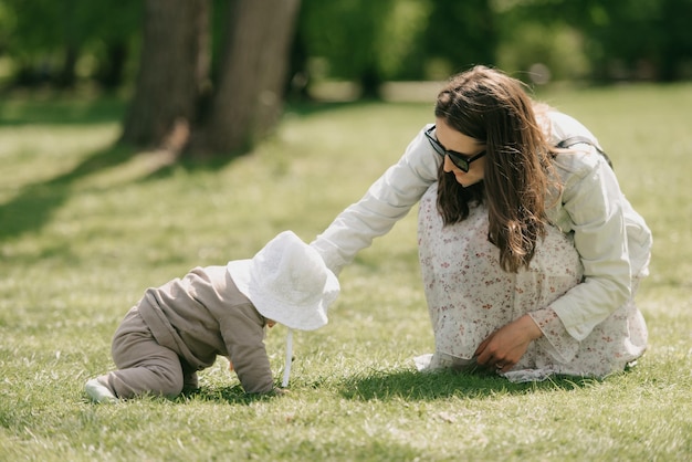 A young mother is playing with her 7month daughter in the meadow