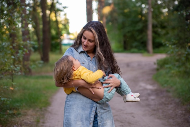 Photo young mother is spinning with a baby in her arms happy mom dancing with toddler on the background of