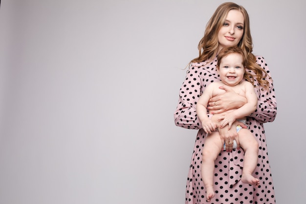 Young mother keeping child on hands and laughing