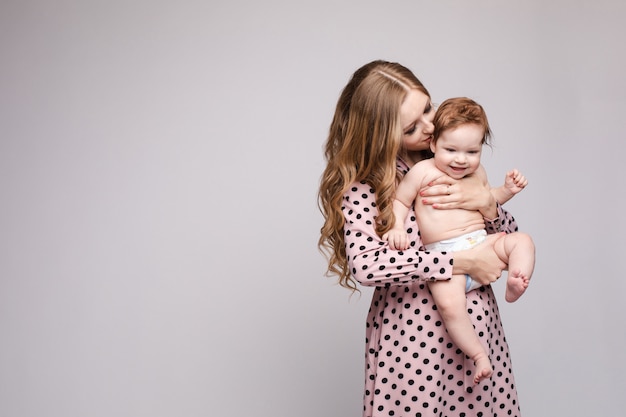 Young mother keeping child on hands and laughing