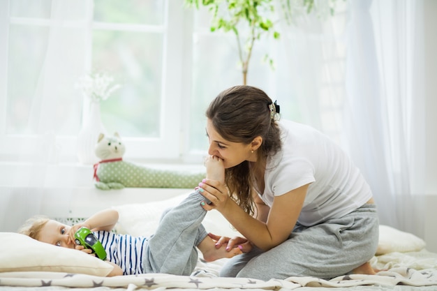 Young mother kissing her baby lying on the bed