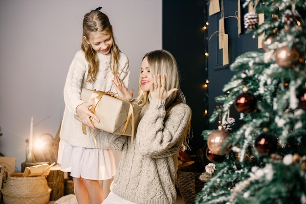若い母親と家でクリスマス ツリーに座っている少女