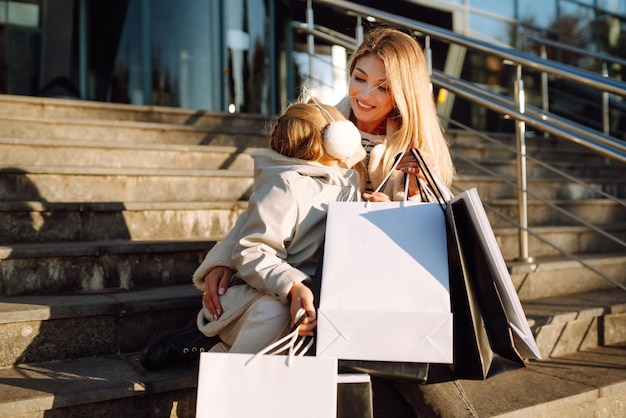 쇼핑을 한 후 쇼핑 가방을 들고 있는 젊은 어머니와 어린 소녀 스프링 스타일 소비주의