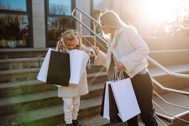 Foto giovane madre e bambina con le borse della spesa dopo lo shopping consumismo in stile primaverile