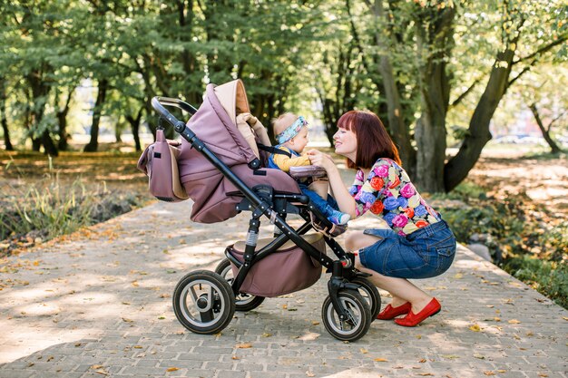 Young mother looking at her child in a baby stroller