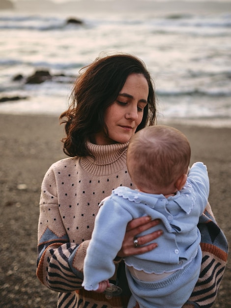 Young mother looking lovingly and tenderly at her baby on the beach vertically