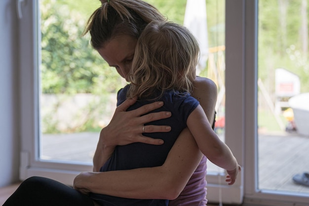 Young mother lovingly hugging her toddler daughter