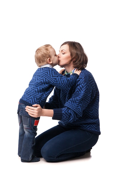 Giovane madre che bacia amorevolmente il suo piccolo figlio. isolato su bianco