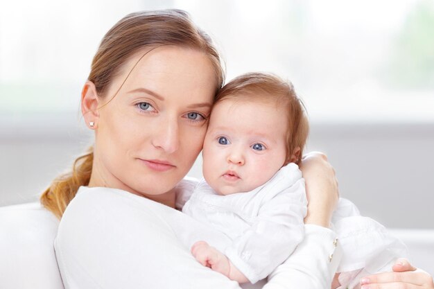 Young mother and newborn baby in white bedroom