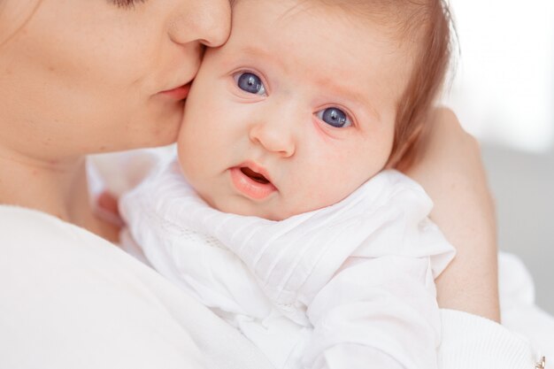 Young mother and newborn baby in white bedroom 