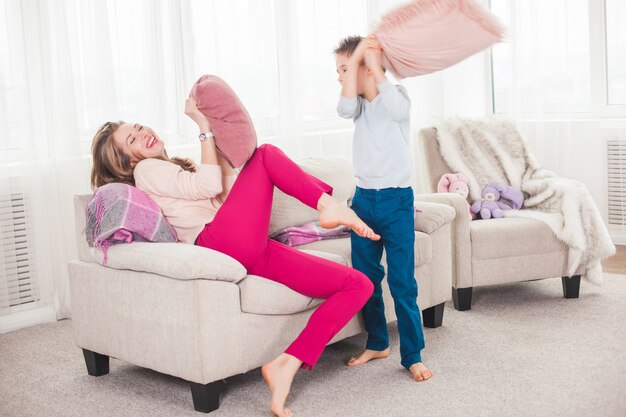 Молодая мать играет в активные игры с сыном. Веселая семья в помещении весело.