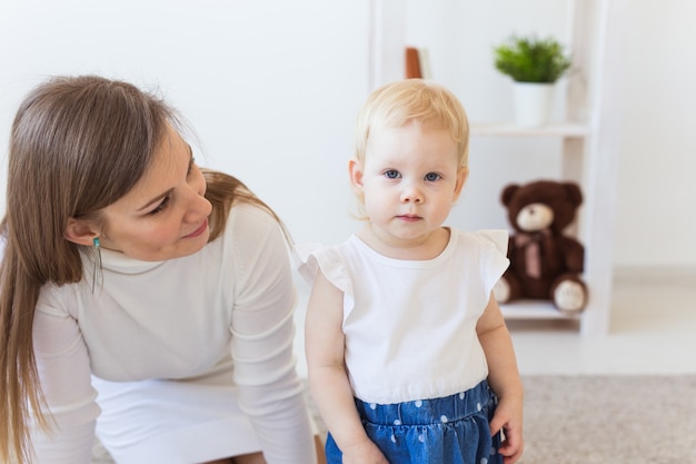 家で女の赤ちゃんと遊ぶ若い母親