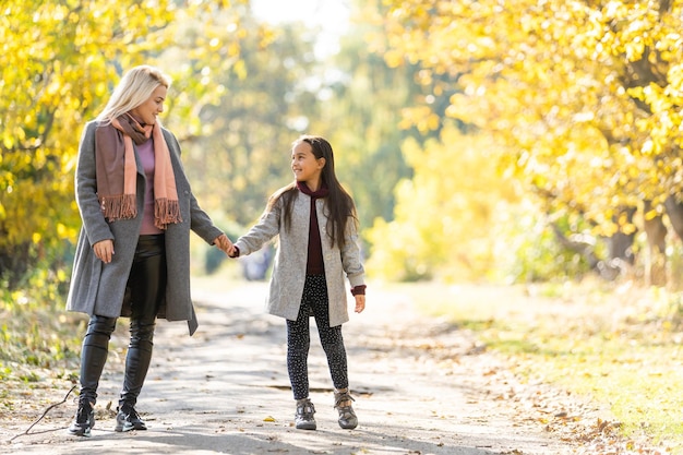 Young mother playing with her daughter in autumn park.