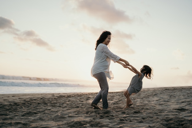 海沿いの小さな女の子と遊ぶ若い母親