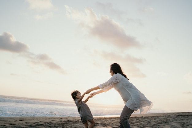 海沿いの小さな女の子と遊ぶ若い母親