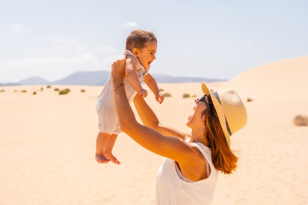 Young mother playing with her son on vacation in the dunes of Corralejo Natural Park, Fuerteventura, Canary Islands. Spain