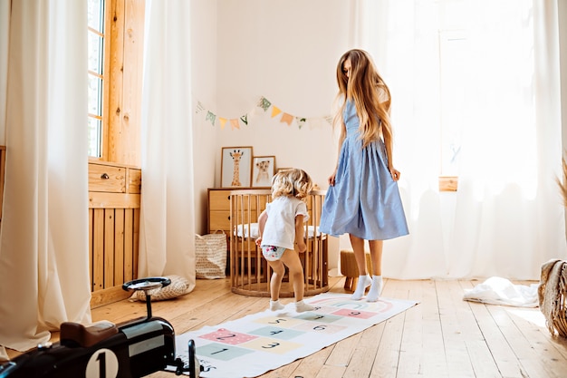 Young mother playing with little child at home