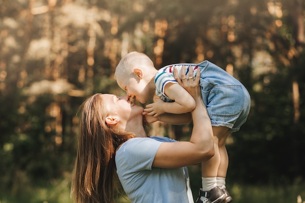 A young mother plays with her young son in the park in the summer