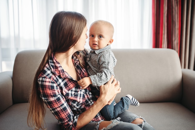 若い母親は、屋内の小さな男性の子供と遊ぶ。ママと息子の家で一緒に幸せ、一体感