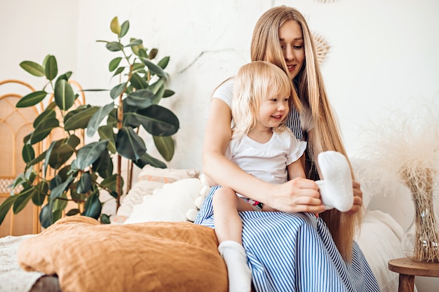 Young mother putting on socks to her child