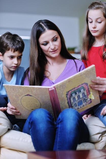 young mother read book to their kids at modern new home living room indoor