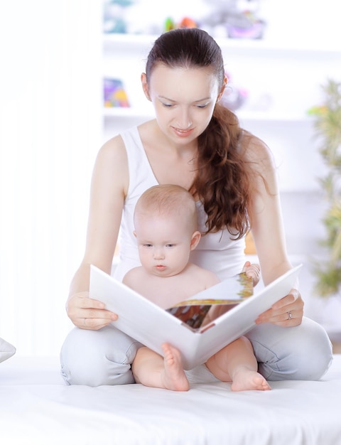 Young mother reads a book to her little daughter