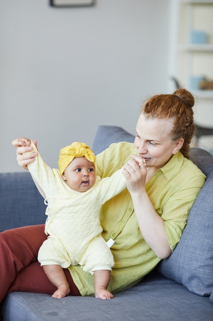 ソファに座って、リビングルームで子供と遊ぶ若い母親