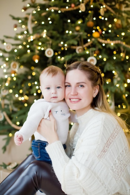 Young mother and son near Christmas tree Happy family waiting for Christmas and New Year