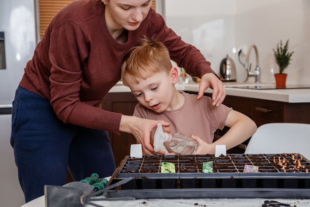 Young mother and son playing with dirt prepared for seeds.