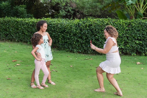 Young mother taking a photo of her daughters outdoors