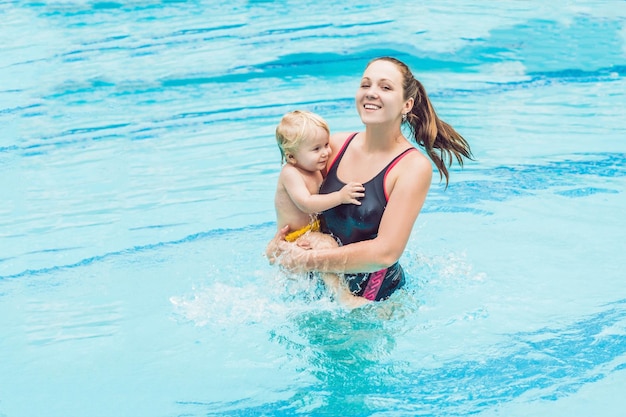 젊은 어머니는 어린 아들에게 수영장에서 수영하는 법을 가르친다