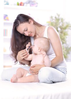 La giovane madre insegna al bambino a stare in piedi. il concetto di maternità