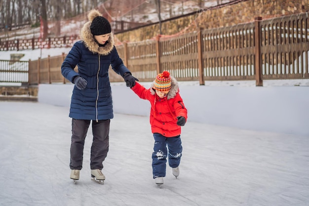 young mother teaching her little son ice skating at outdoor skating rink Family enjoy winter on icerink outdoors