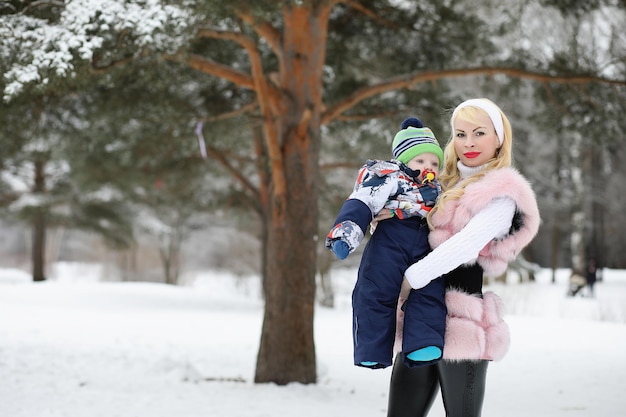 Young mother walks on a winter day with a baby in her arms in the park