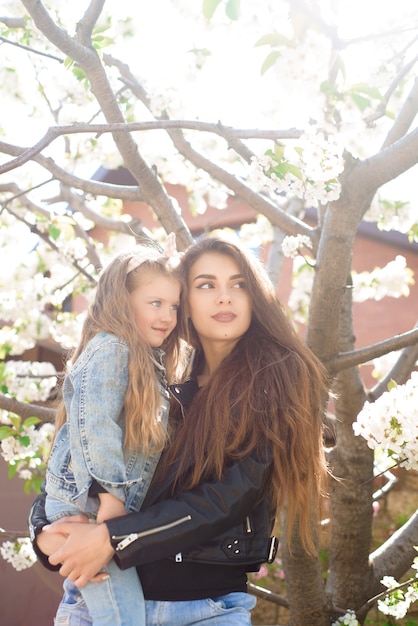 Young mother with adorable daughter in park with blossom tree