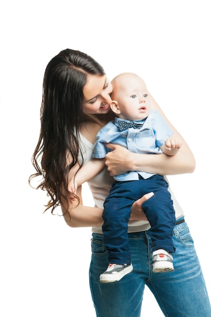 Young mother with cute baby boy huging and posing over white background