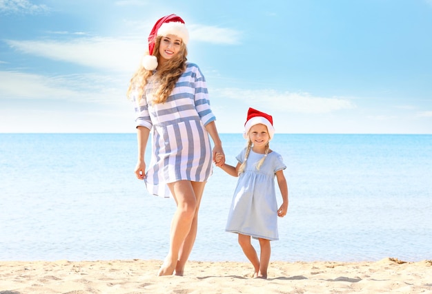 Young mother with cute girl on beach. Christmas celebration concept