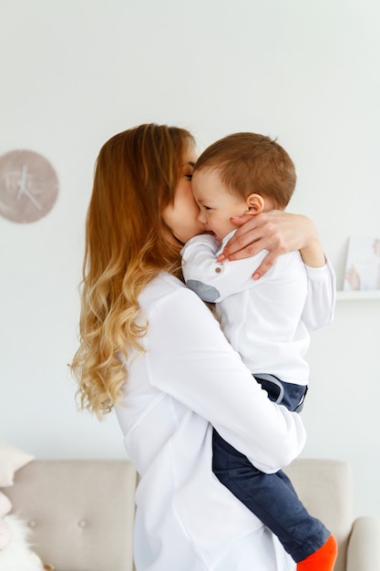 A young mother with a cute little son is having fun in a bright cozy living room