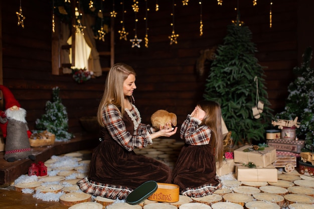 Foto giovane madre con sua figlia in camicie a scacchi in stile rurale. la mamma fa un regalo di natale a sua figlia.